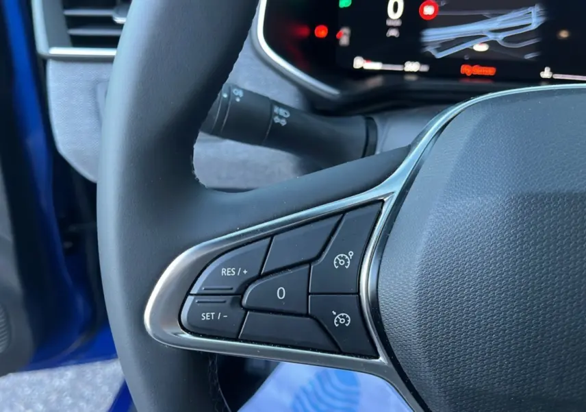 Gros plan sur les commandes de régulateur de vitesse au volant cuir d'une Renault Clio Bleu Iron 2025.