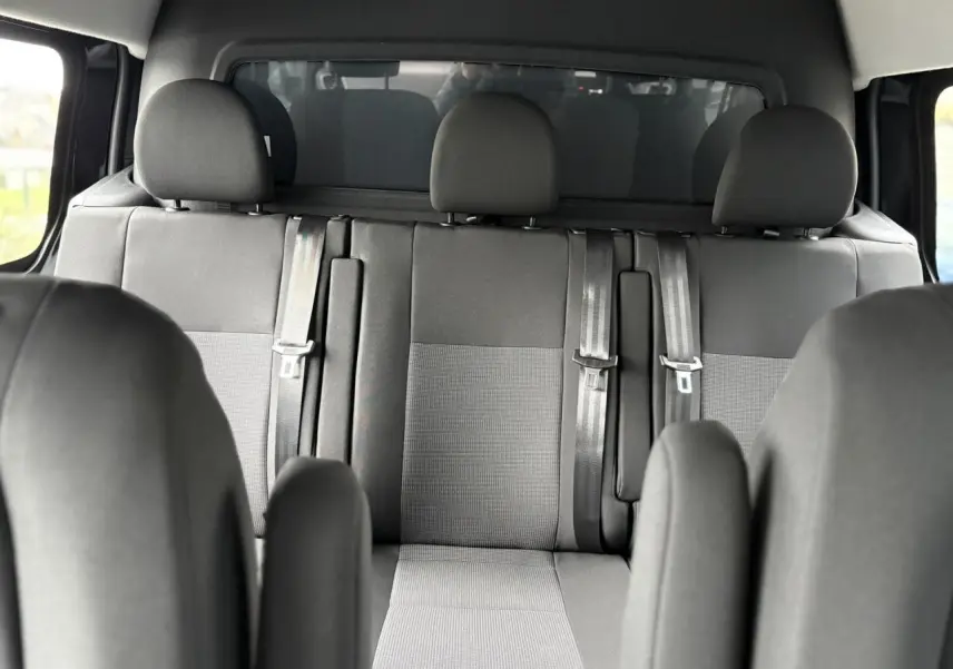 Vue intérieure sur la banquette arrière grise du Citroën Jumpy XL 2025 avec appuie-têtes et ceintures de sécurité.