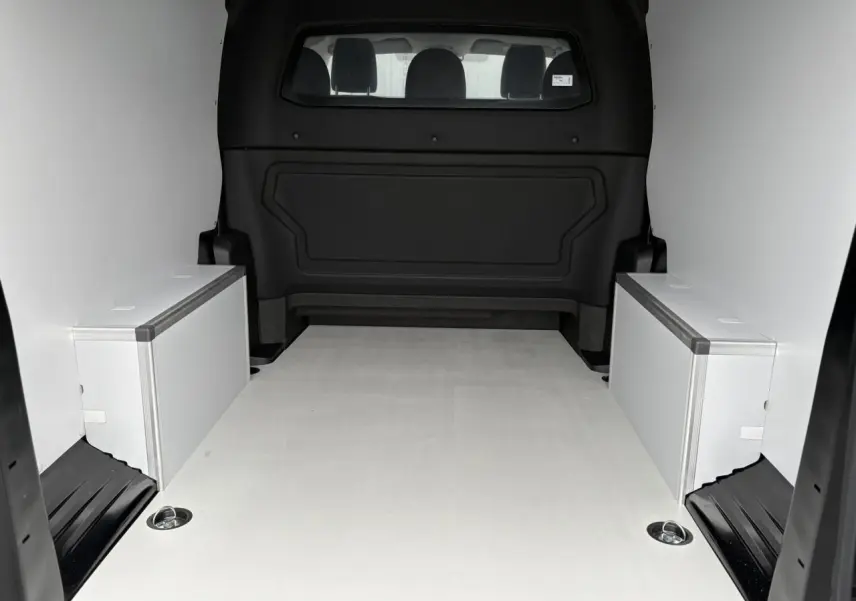 Vue intérieure arrière du Citroën Jumpy XL noir Perla montrant l’espace de chargement avec plancher bois et coffrages latéraux blancs.