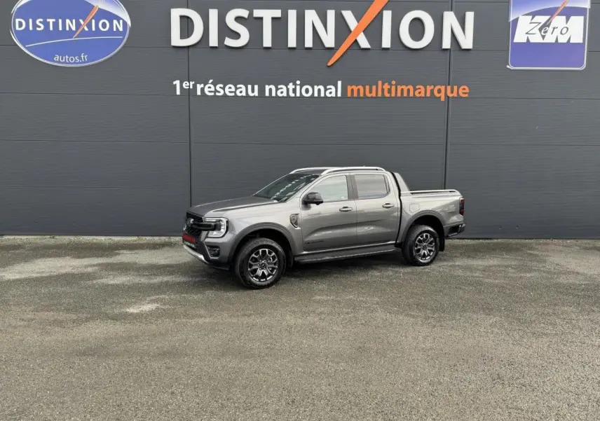 Ford Ranger 2025 gris en vue de profil droit, pick-up Wildtrak avec jantes noires et logo rouge sur calandre.
