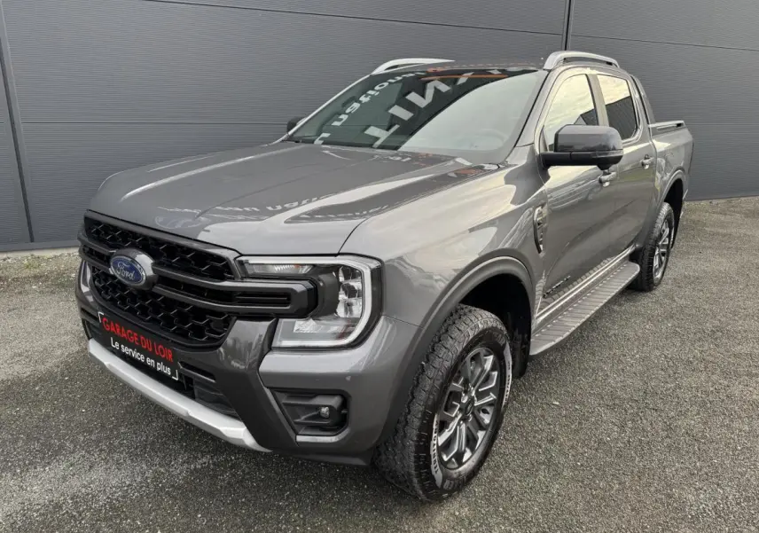 Ford Ranger 2025 gris, vue 3/4 avant droit, avec calandre noire et marchepieds latéraux métalliques.