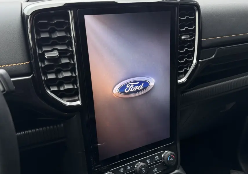 Vue rapprochée de l'écran tactile vertical central noir avec logo Ford, entouré de la console intérieure noire du Ford Ranger.