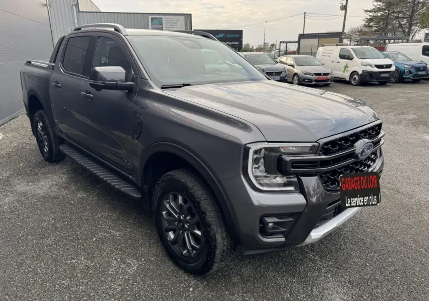 Ford Ranger Wildtrak gris foncé en 3/4 avant droit, avec calandre noire et jantes alliage sombres.
