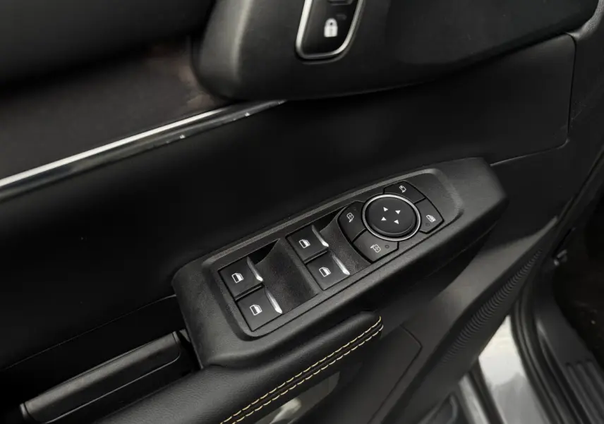Gros plan sur la commande des vitres et rétroviseurs côté conducteur du Ford Ranger 2025, intérieur noir avec surpiqûres jaunes.
