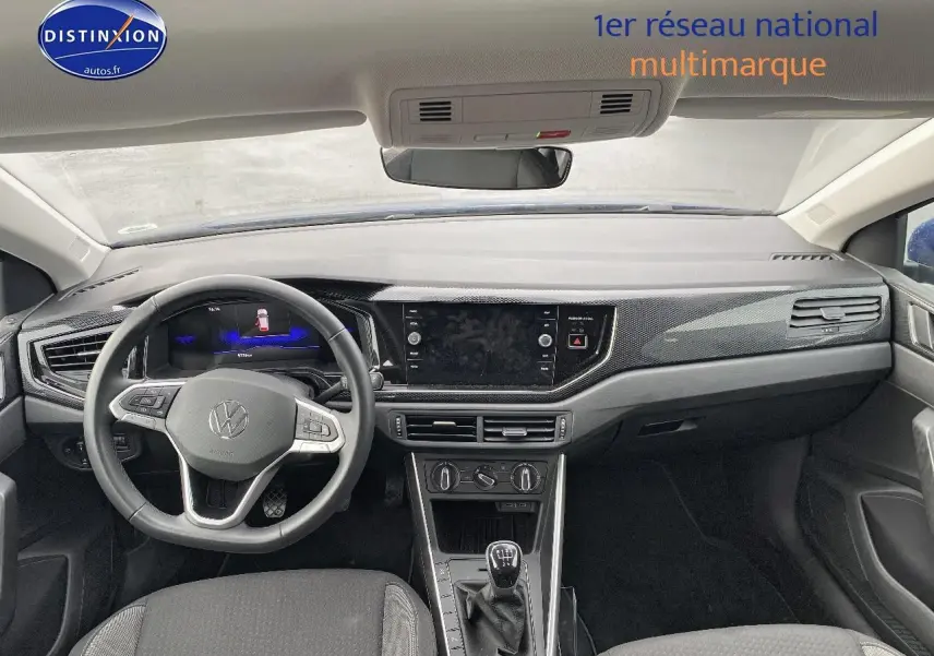 Vue intérieure avant du tableau de bord et volant cuir multifonction de la Volkswagen Polo bleu récif, avec levier de vitesse manuel.