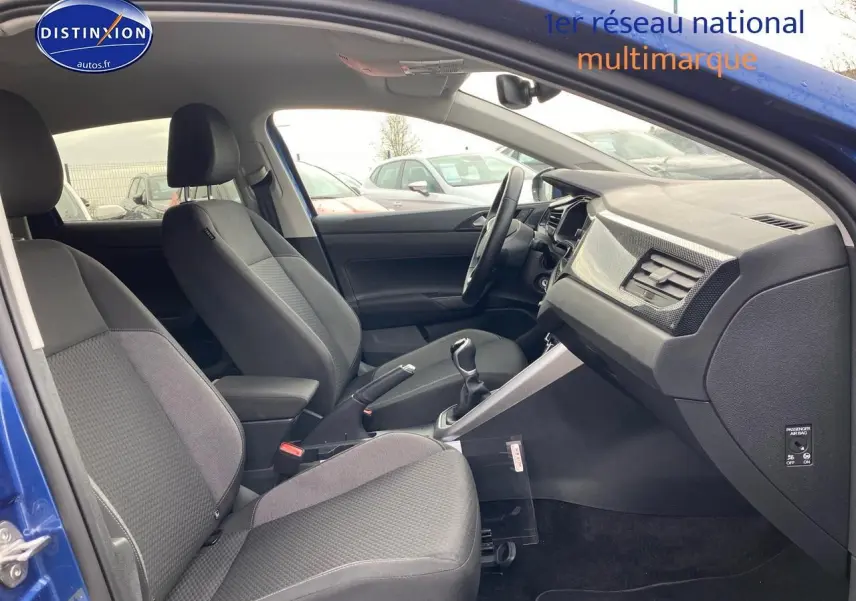 Intérieur avant de la Volkswagen Polo bleu récif, vue côté droit montrant sièges tissu noir et tableau de bord moderne.