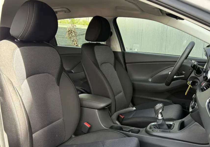 Vue intérieure côté droit montrant les sièges avant noirs et gris et la console centrale d'une Hyundai i30 SW T-GDI 120 Modern 2025.