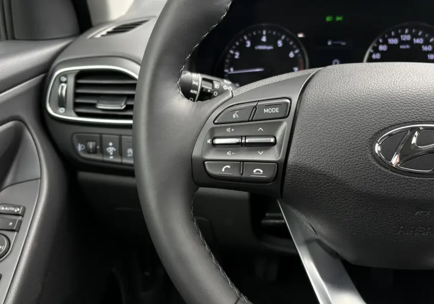 Gros plan sur le volant cuir gris avec commandes intégrées et tableau de bord numérique de la Hyundai i30 SW T-GDI 2025.