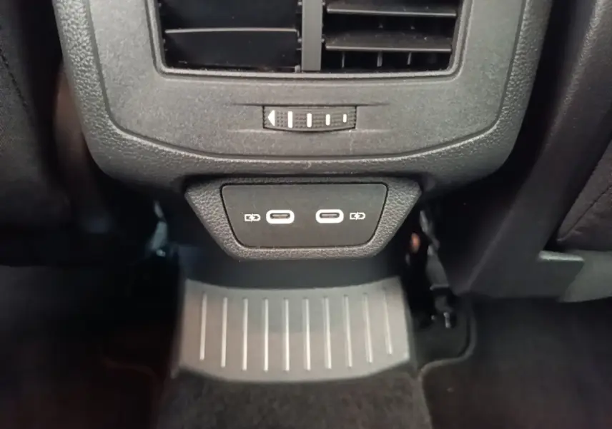 Vue rapprochée des ports USB-C doubles et de la sortie d'air arrière dans l'habitacle noir du Volkswagen T-Roc bleu.