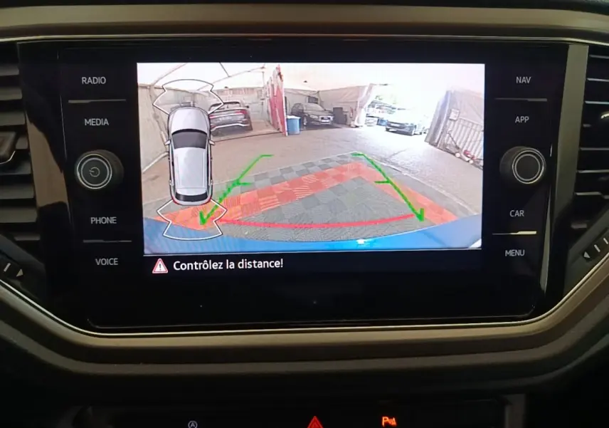 Écran tactile intérieur montrant la caméra de recul du Volkswagen T-Roc bleu, vue arrière avec guidage de trajectoire.