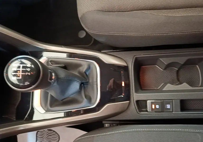 Gros plan sur la console centrale du Volkswagen T-Roc bleu 2020, avec levier de vitesse manuel et rangement porte-gobelets.