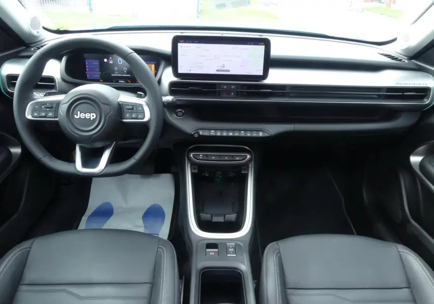 Intérieur noir du Jeep Avenger 2024 vu de face, tableau de bord moderne avec écran tactile central et volant multifonction.