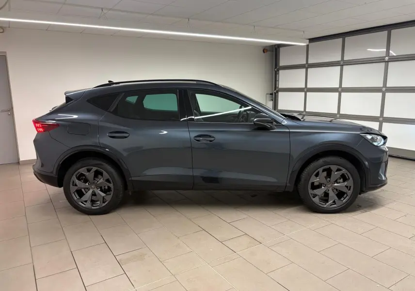 Profil côté gauche du CUPRA Formentor 2025 gris magnétique, avec jantes noires et attelage escamotable visible.