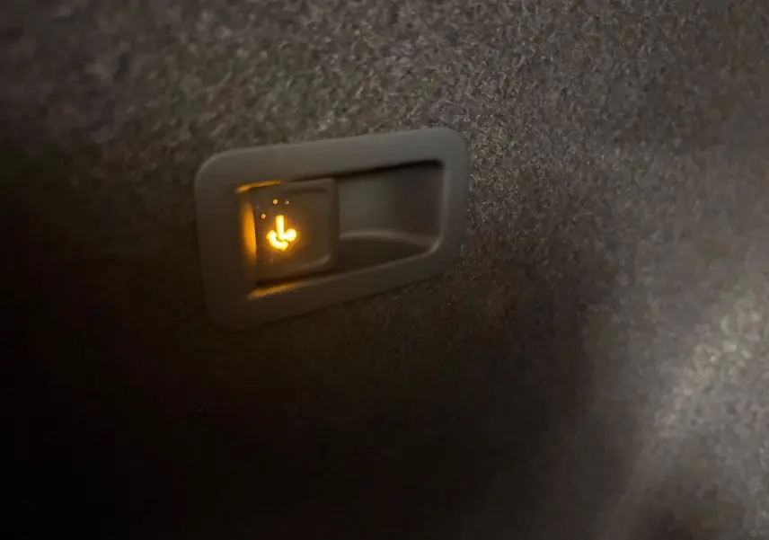Gros plan sur l'interrupteur lumineux de rabattement des sièges arrière dans le coffre du CUPRA Formentor gris magnétique.