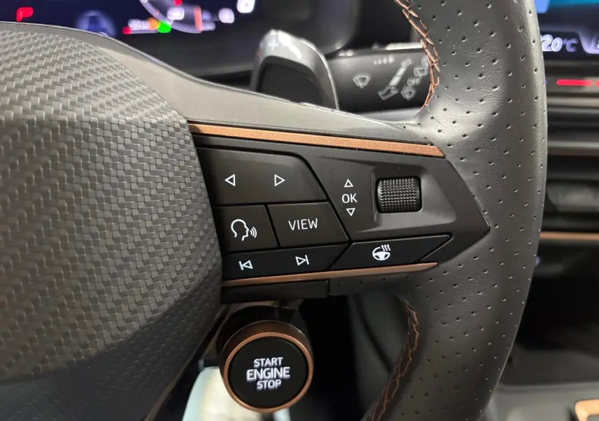 Gros plan sur le volant perforé et les commandes multifonctions du CUPRA Formentor gris magnétique, avec bouton start/stop visible.