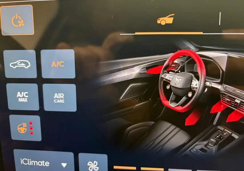 Affichage tactile montrant l'intérieur avant droit du CUPRA Formentor 2025 avec volant et commandes en surbrillance rouge.