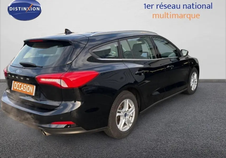 Ford Focus SW noire vue en 3/4 arrière droit, avec barres de toit et jantes alliage 16 pouces.