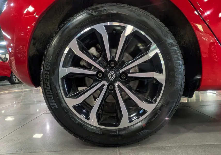 Gros plan sur la roue avant droite de la Renault Clio V Rouge Flamme, avec jante alliage bicolore et logo Renault central.