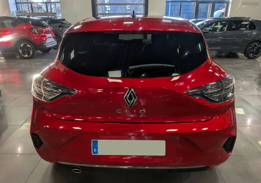 Vue arrière d'une Renault Clio V rouge flamme, avec feux arrière LED et lunette arrière teintée en showroom.