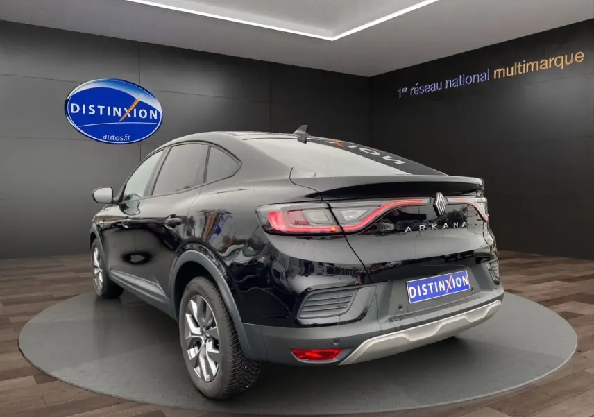 Vue 3/4 arrière droite du Renault Arkana noir 2024 avec feux arrière LED et logo distinctif sur fond showroom.