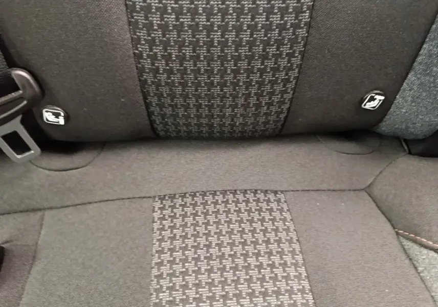 Gros plan sur la banquette arrière noire du Peugeot 3008 2022, tissu à motif central et ceintures visibles.