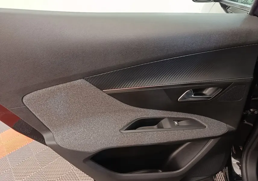 Gros plan sur la porte intérieure côté conducteur du Peugeot 3008 noir, avec habillage tissu et garniture noire.