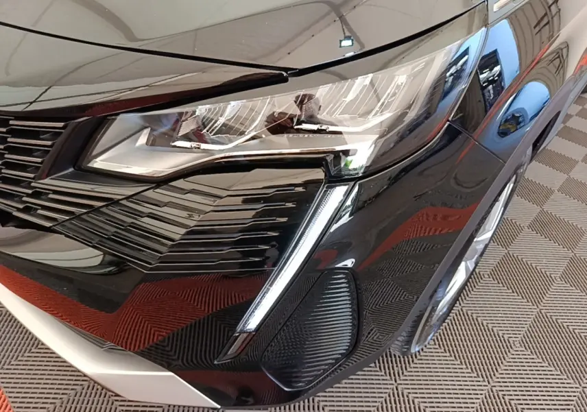 Gros plan sur l'avant droit noir brillant du Peugeot 3008 avec phare LED et calandre distinctive.