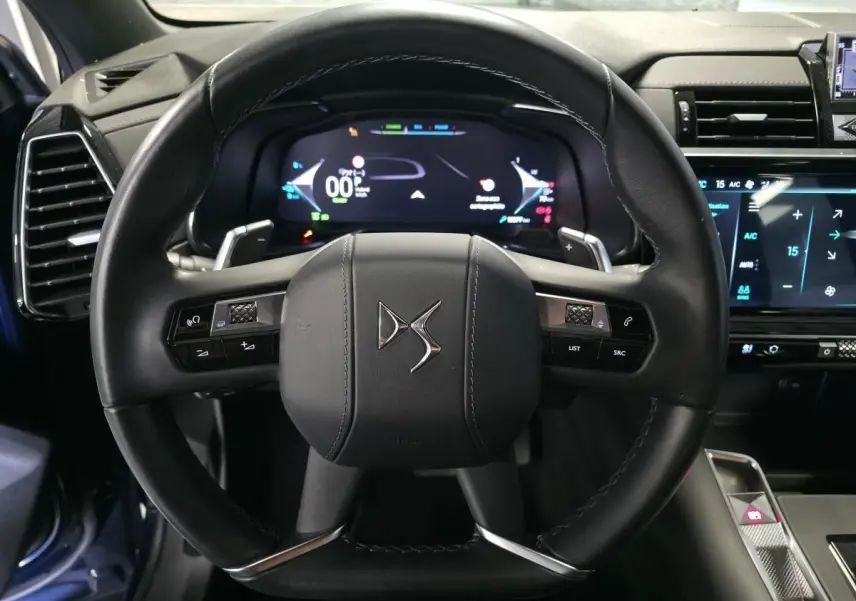 Vue rapprochée du volant en cuir noir du DS7 Crossback 2024 avec commandes intégrées et tableau de bord numérique.