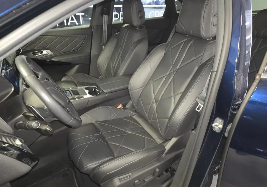 Intérieur avant du DS7 Crossback E-Tense 2024, sièges en cuir noir avec surpiqûres et porte ouverte côté conducteur bleu métallisé.
