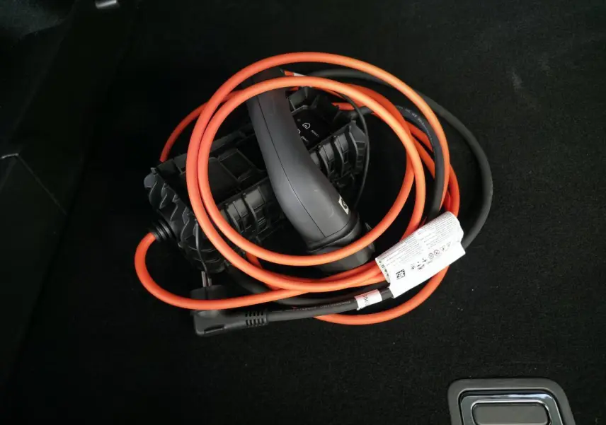 Câble de recharge hybride orange et noir enroulé dans le coffre d'un DS7 Crossback bleu.