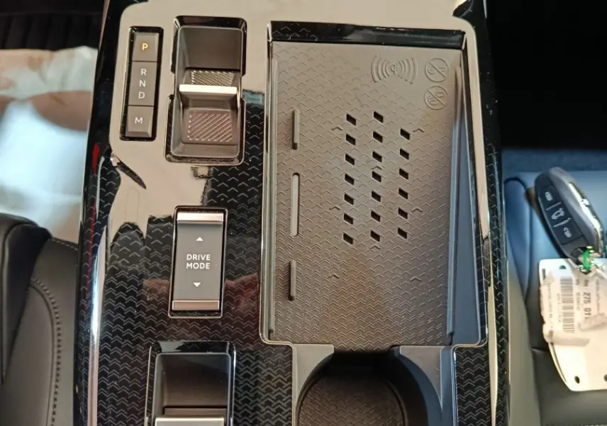 Vue plongeante sur la console centrale noire brillante du Citroën C5 Hybride 2026 avec commandes tactiles et porte-gobelet.