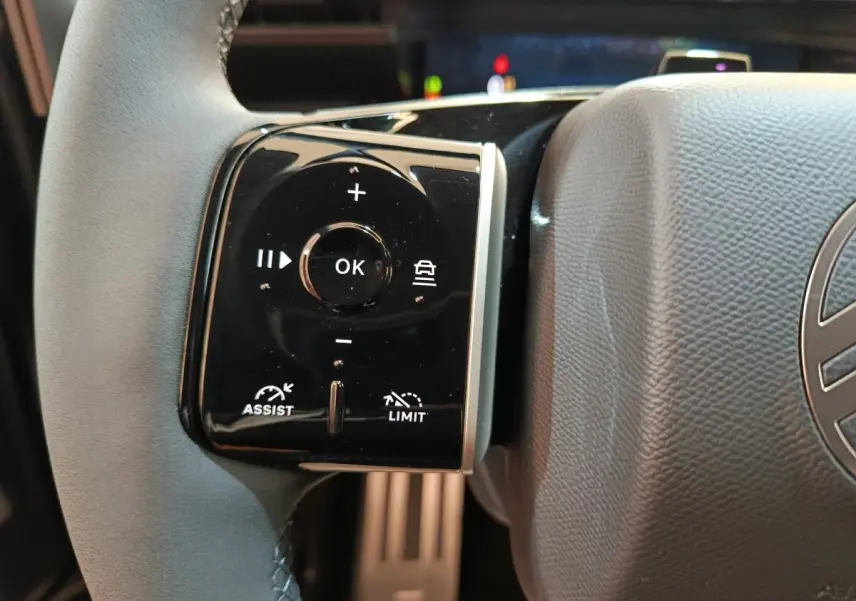 Gros plan sur les commandes gauche du volant cuir de la Citroën C5 Hybride noire, avec boutons multifonctions et régulateur.