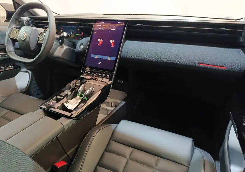 Intérieur avant droit de la Citroën C5 Hybride 2026, tableau de bord moderne avec écran tactile vertical et volant cuir noir.