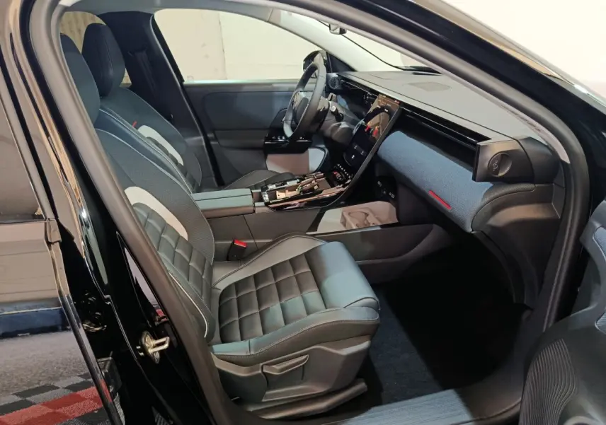 Intérieur avant droit d'une Citroën C5 Hybride noire 2026 avec sièges cuir et grand écran tactile central.
