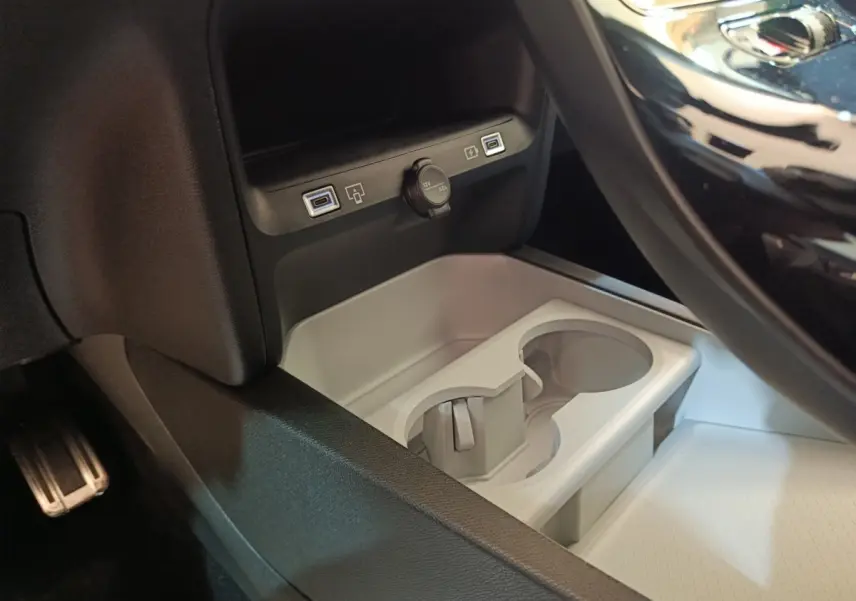 Gros plan sur la console centrale intérieure du Citroën C5 Hybride noir, montrant prises USB et porte-gobelets gris clair.