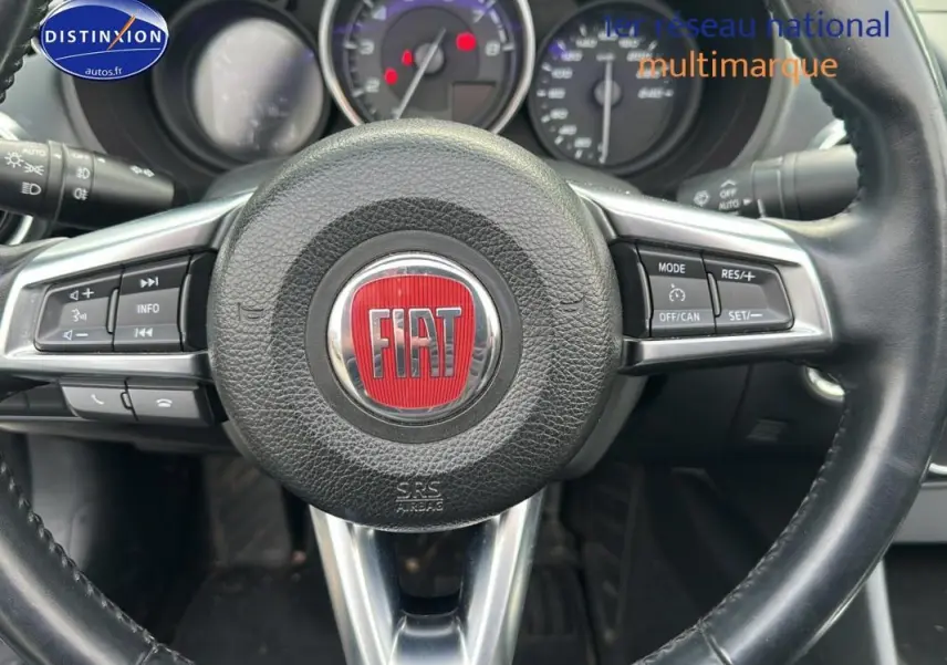 Vue rapprochée du volant cuir multifonctions noir avec logo FIAT rouge au centre du 124 Spider Lusso 2017.