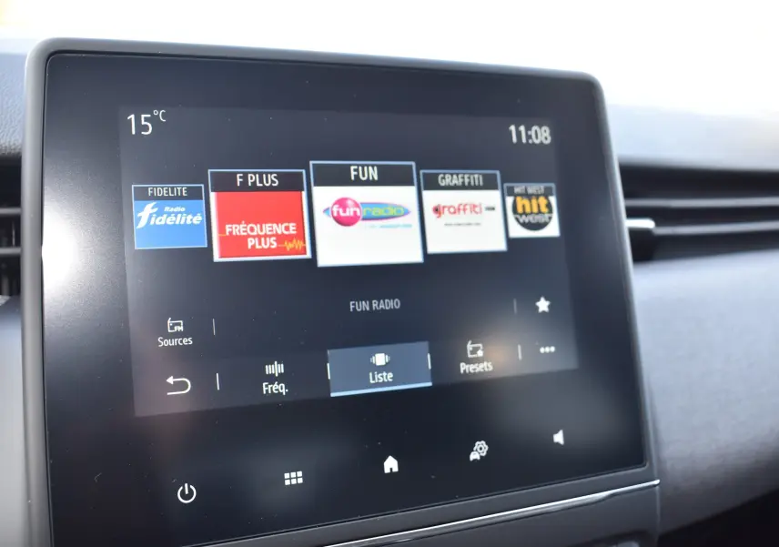Écran tactile central du tableau de bord de la Renault Clio V gris, affichant les stations radio avec interface moderne.