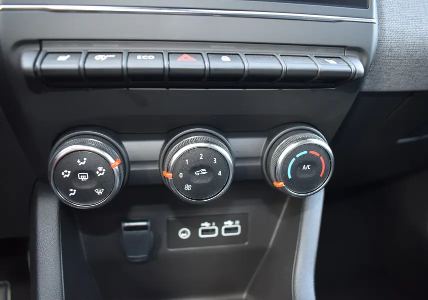 Gros plan sur les commandes de climatisation de la Renault Clio V gris 2024 avec boutons rotatifs et ports USB visibles.