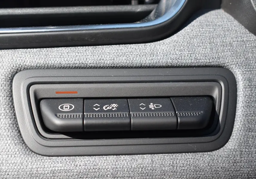 Gros plan sur les commandes de réglage des feux et du tableau de bord dans une Renault Clio V gris 2024.