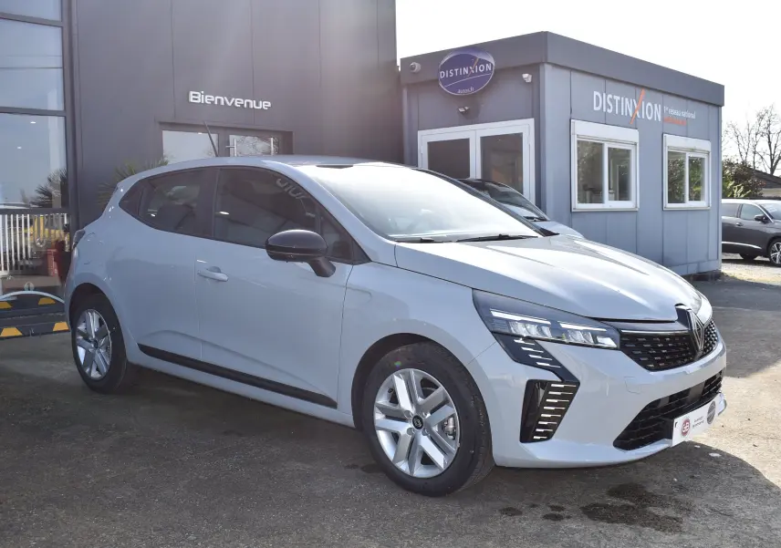 Renault Clio V TCE 90 gris vue 3/4 avant droit, avec calandre noire et feux LED distinctifs.