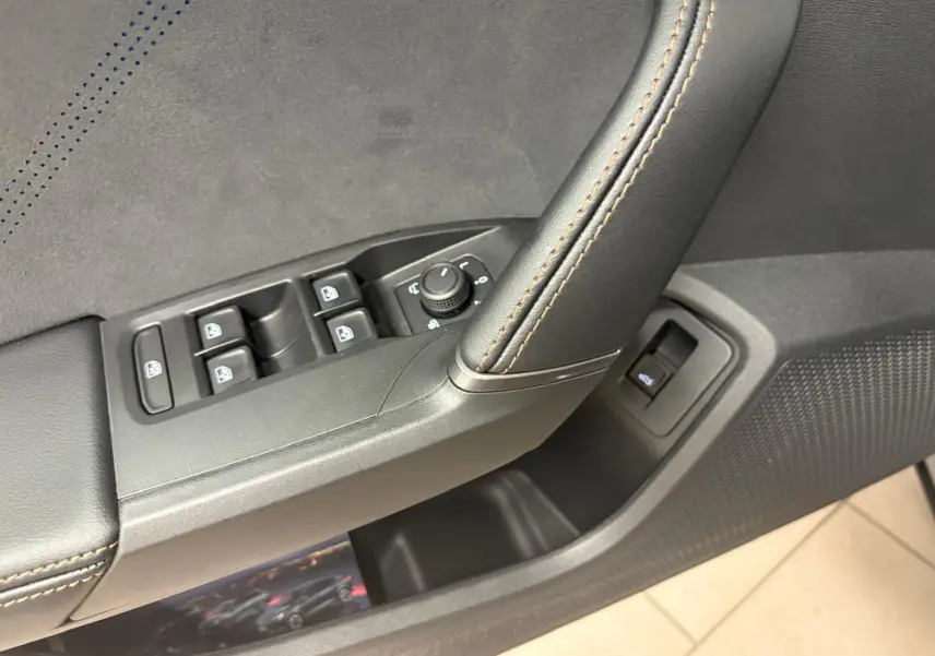 Gros plan sur la commande des vitres et rétroviseurs côté conducteur du CUPRA Formentor 2025 avec surpiqûres orange.