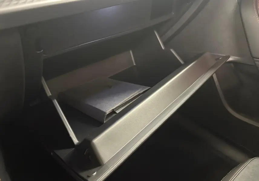 Gros plan sur la boîte à gants ouverte du CUPRA Formentor 2025, avec un livret à l'intérieur et sellerie noire.