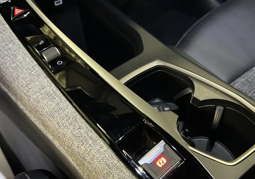 Gros plan sur la console centrale intérieure du Peugeot 3008 bleu Ingaro, montrant les commandes et porte-gobelets.