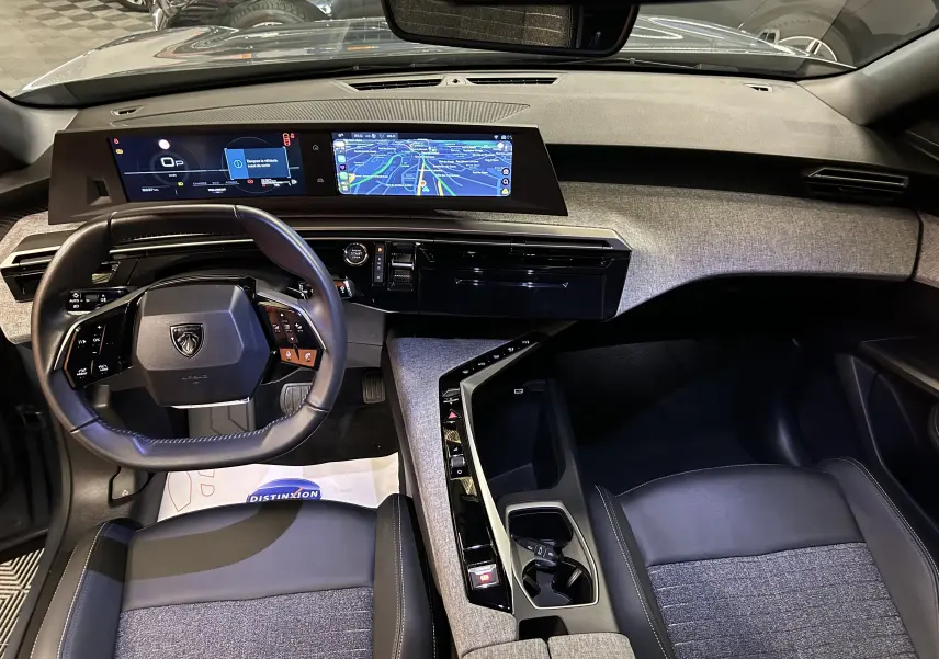 Vue intérieure du tableau de bord et volant du Peugeot 3008 III Hybrid 145 Allure en tissu gris et cuir noir avec écran tactile panoramique.