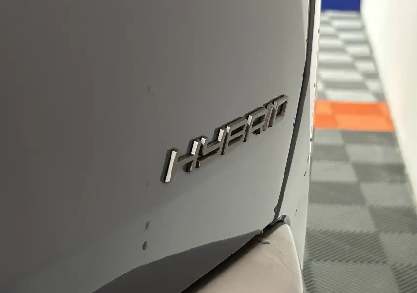 Gros plan sur l’inscription HYBRID à l’arrière droit d’un Peugeot 3008 bleu Ingaro 2025.