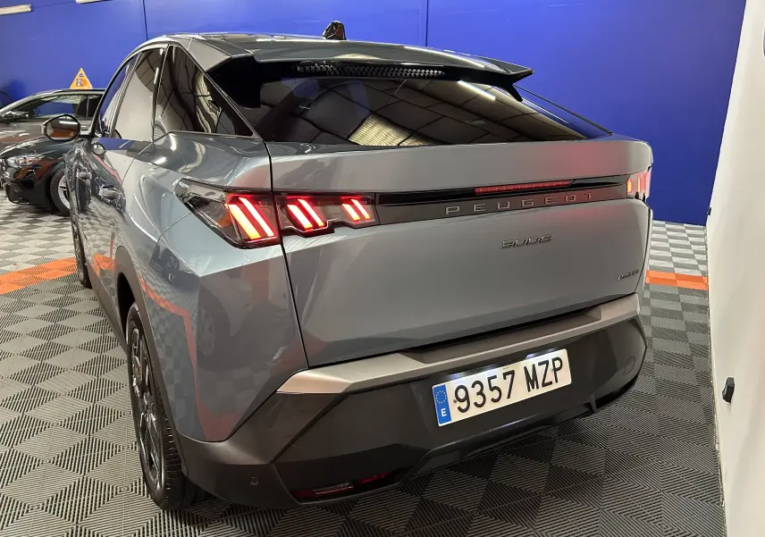 Vue 3/4 arrière gauche du Peugeot 3008 bleu Ingaro avec feux arrière LED allumés dans un showroom.