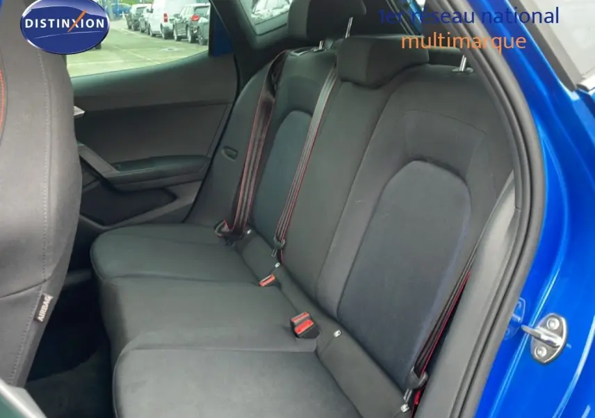 Vue intérieure côté droit sur la banquette arrière tissu noir avec ceinture rouge d'un SEAT Arona bleu saphir métallisé.