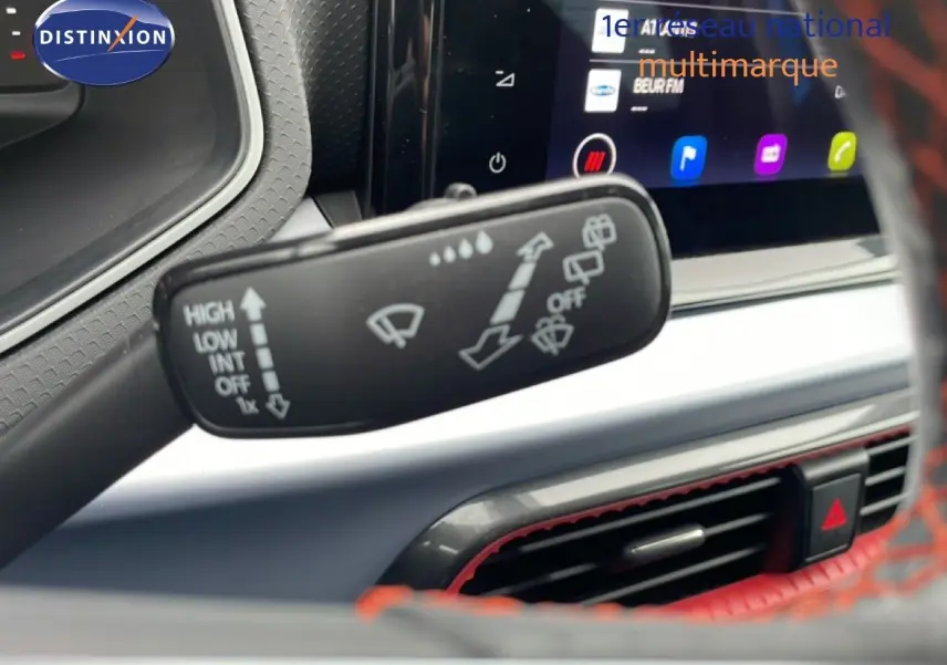 Gros plan sur la commande d’essuie-glace dans l’habitacle du SEAT Arona bleu saphir avec écran tactile et volant rouge.