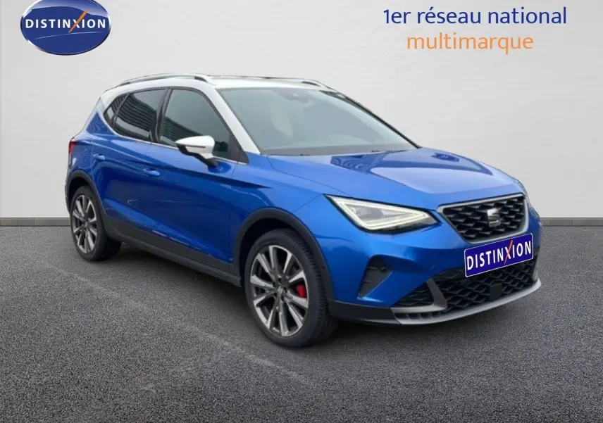 Vue 3/4 avant gauche d’un SEAT Arona bleu saphir métallisé avec toit blanc et jantes alliage, sur fond neutre.