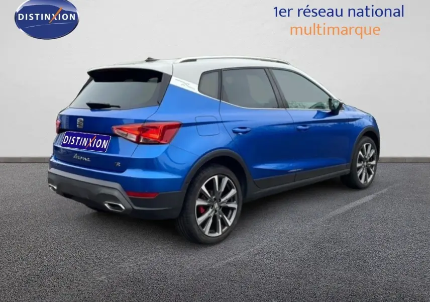 Vue 3/4 arrière droite d’un SEAT Arona bleu saphir métal avec toit blanc et jantes alliage distinctives.